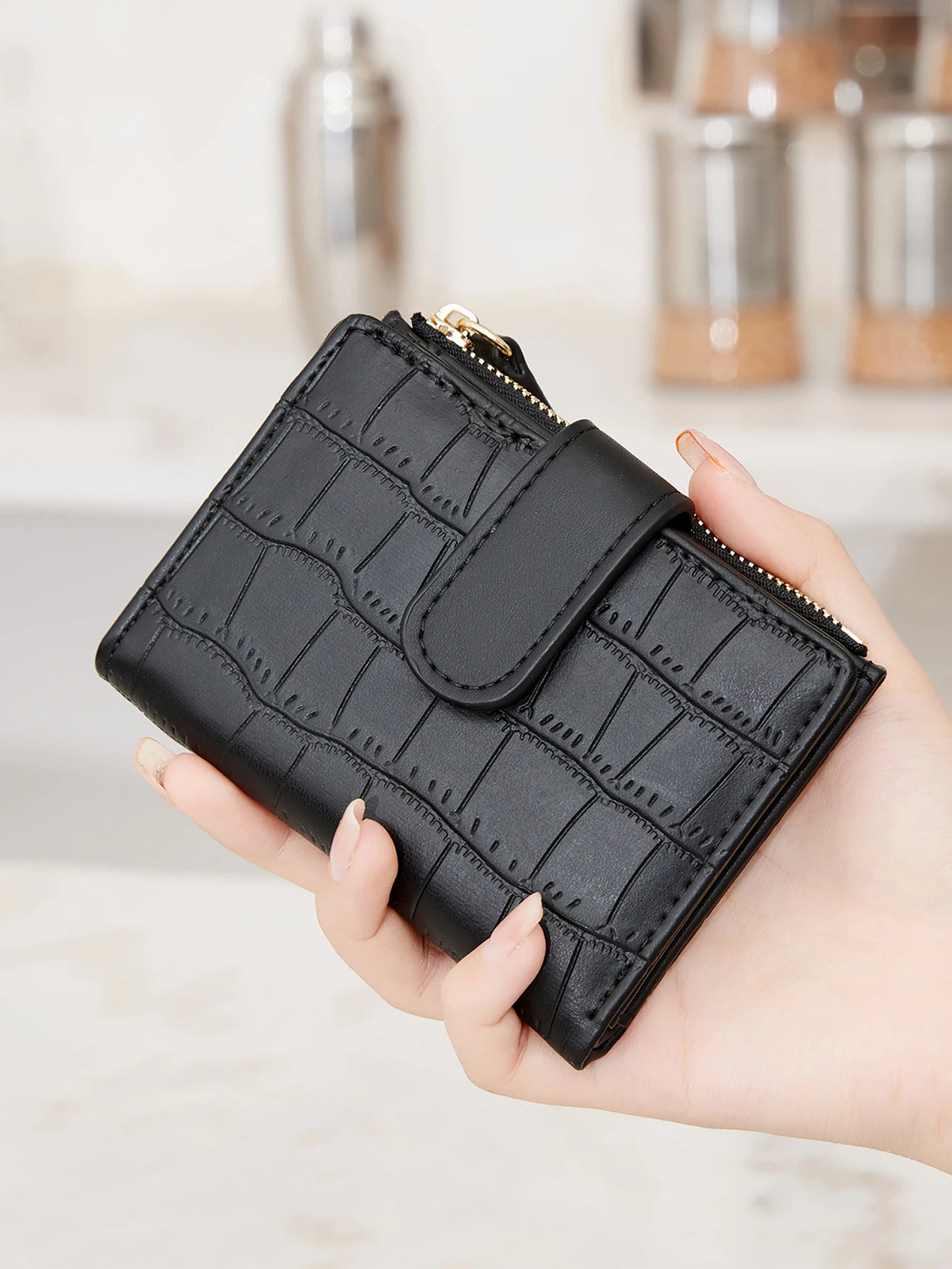 A hand holds a black PU leather bifold wallet with a zipper closure.