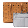 A tan patterned leather handbag is shown next to a gray fabric travel season organizer pouch.