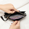 A hand is opening a black PU leather coin purse and card holder filled with cash and cards.