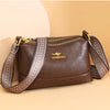 A brown luxury PU leather crossbody handbag with gold hardware and patterned strap resting on a light background.