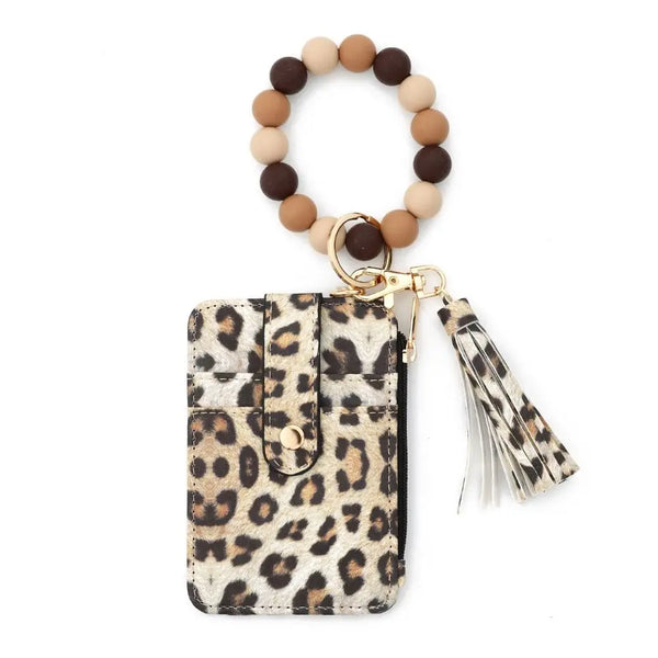 A leopard print faux leather card holder and tassel keychain with a beaded bracelet.