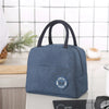 A dark blue insulated lunch bag with black handles resting on a light surface.