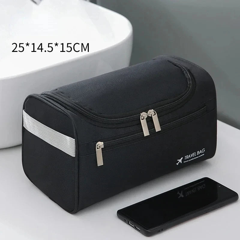 A black durable hanging leather toiletry bag next to a smartphone and a white ceramic sink.