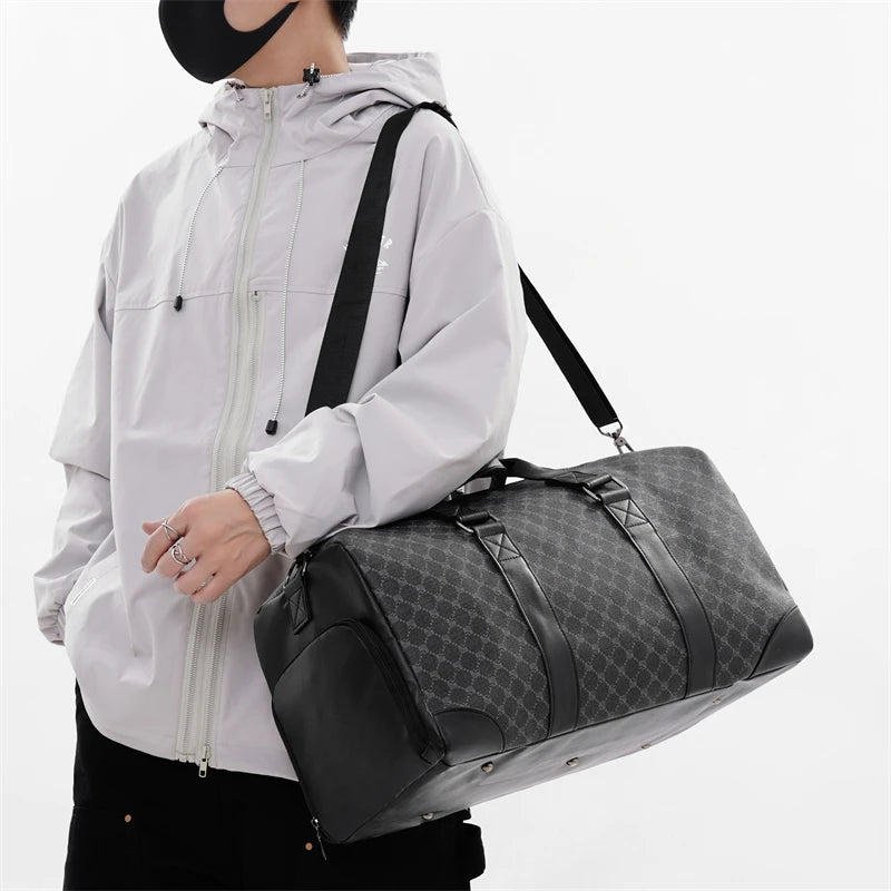 A man wearing a white hooded jacket holds a black leather-trimmed travel duffle bag.