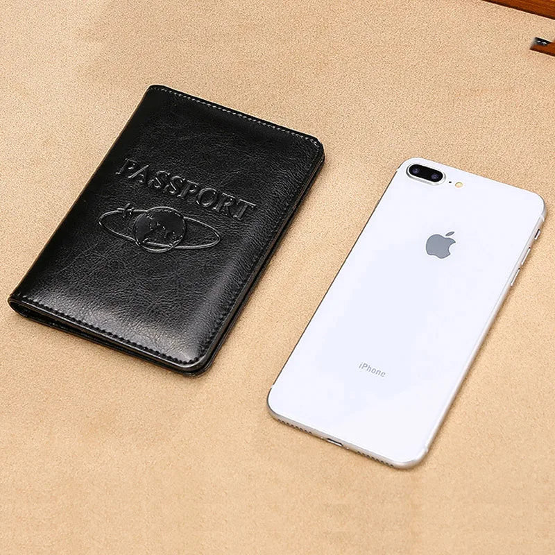 A black genuine leather passport holder next to a white iPhone on a beige surface.