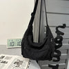 A black large capacity cotton canvas shoulder crossbody bag hanging against a gray vertical surface.