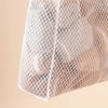 A close-up view of a white honeycomb mesh laundry bag with a wall-mount hook.