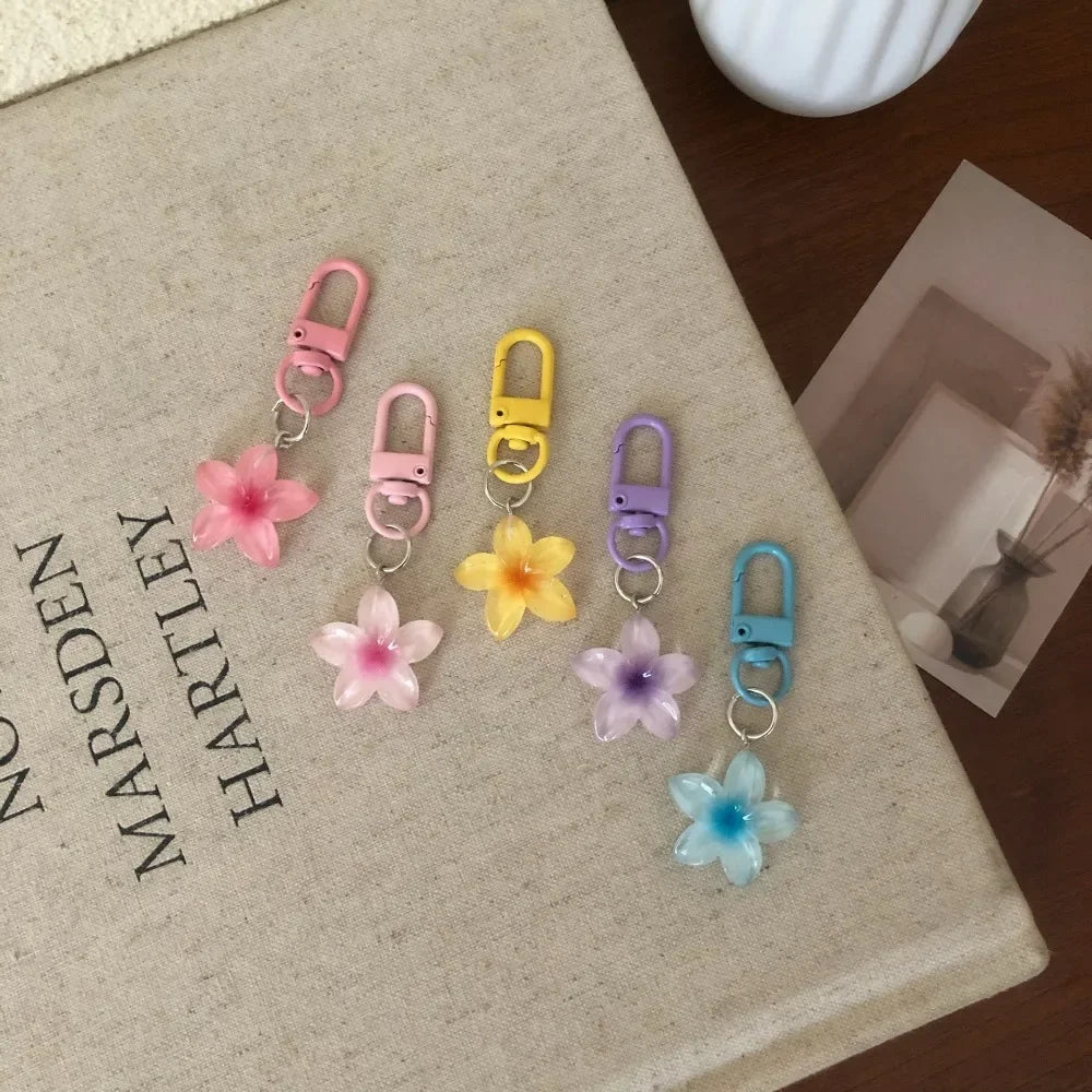 A collection of colorful resin flower keychains in pink, yellow, purple, and blue hanging from metal split rings.