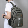 A man wearing a white t-shirt is holding a gray backpack with orange accents.