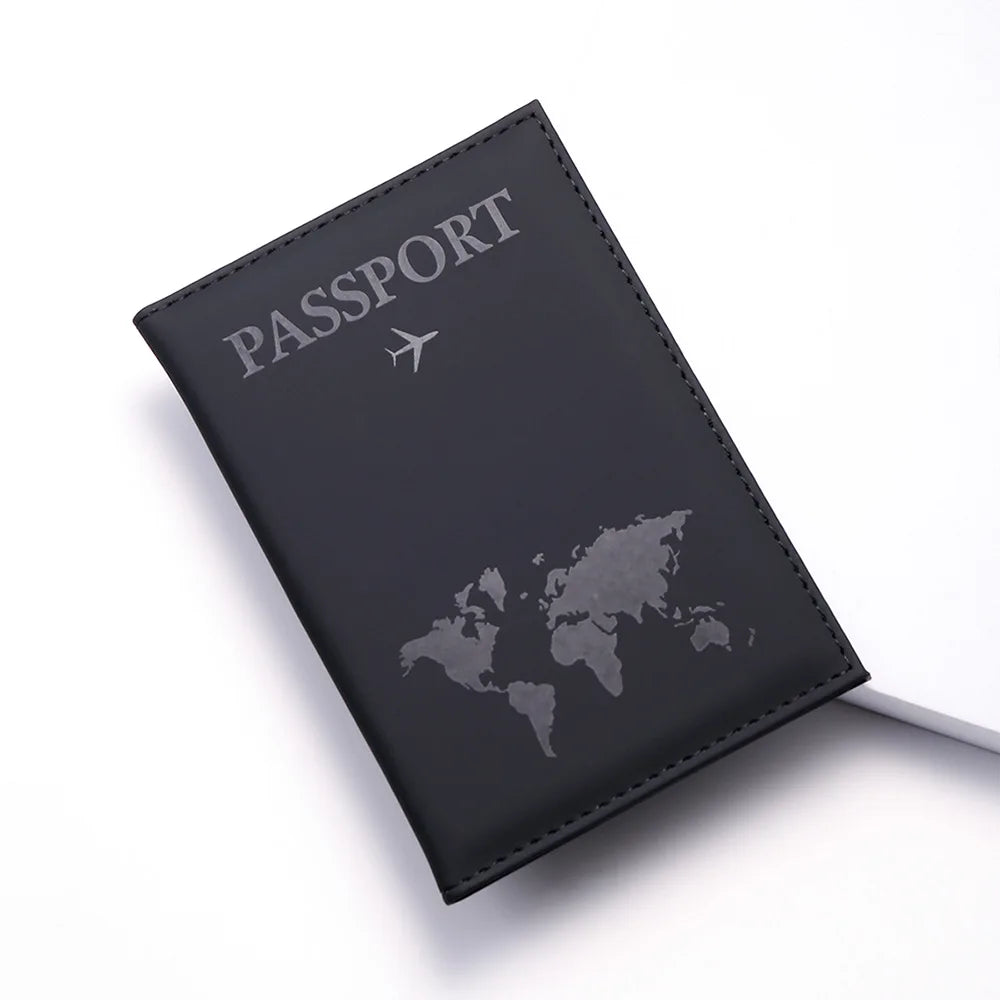 A black leather passport wallet with silver embossed text and a faint world map design.