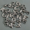 A collection of stainless steel alphabet letter charms with lobster clasps arranged on a gray surface.