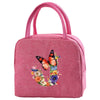 A pink insulated canvas lunch bag with pink fabric handles and a floral butterfly design.