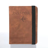 A brown leather passport organizer with a black strap and embossed text on the cover.
