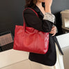 Eine Frau hält eine rote Vintage-PU-Leder-Handtasche neben einem schwarzen Blazer.