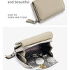 Cartera de cuero genuino color beige con cierre, abierta mostrando un bolsillo trasero lleno de monedas.