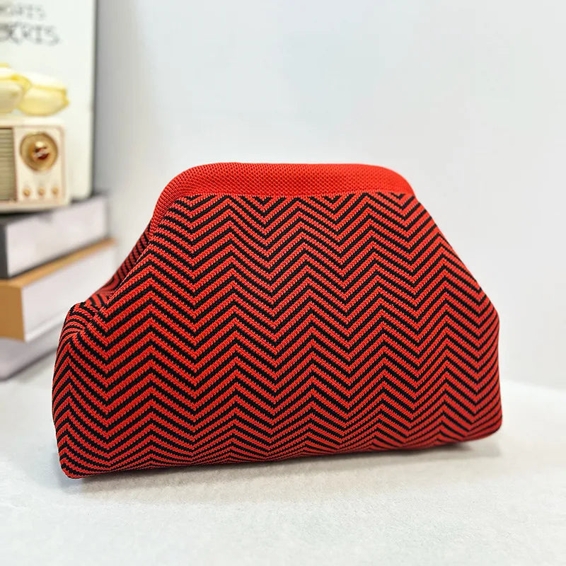 Pochette de plage crochet à chevrons rouge et noir sur une surface blanche.