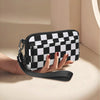 A hand holds a black and white checkered multi-card wallet with a clear ID window.