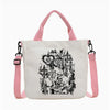 Bolso tote de lona blanca con tiras rosas y una ilustración en línea negra de un cráneo y una figura.
