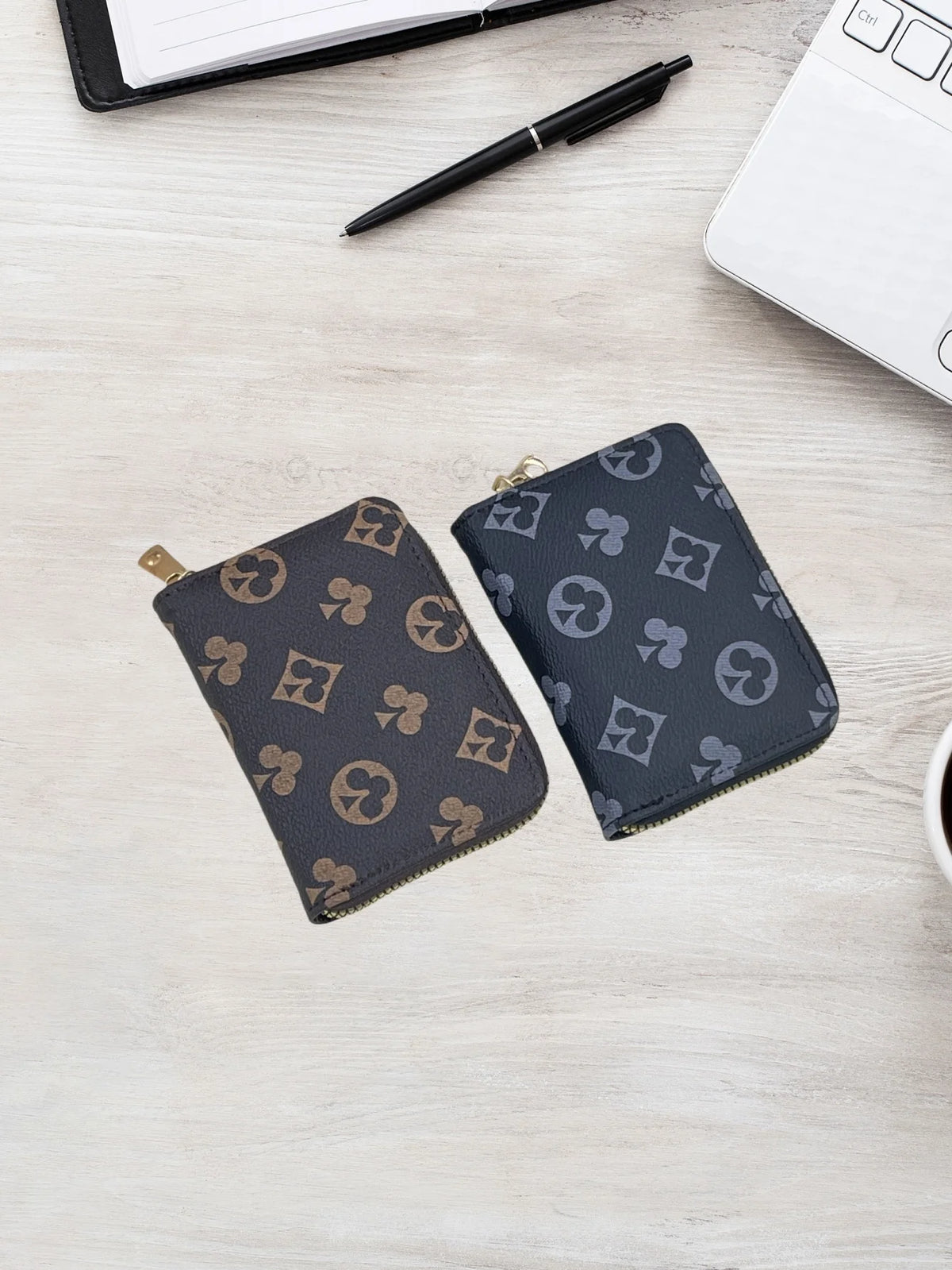 A dark gray zippered card holder wallet with a repeating geometric pattern is placed on a light wooden surface next to a whit