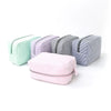 A collection of four cosmetic bags in pastel stripes, including mint green, purple, gray, and pink.