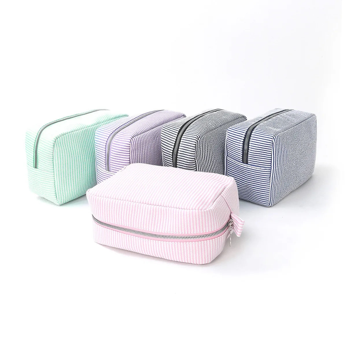 A collection of four cosmetic bags in pastel stripes, including mint green, purple, gray, and pink.