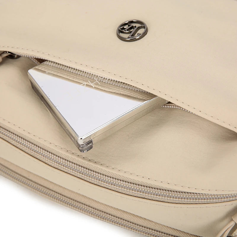 Bolso cruz impermeable de nylon beige claro con logo plateado y ventana de plástico transparente.