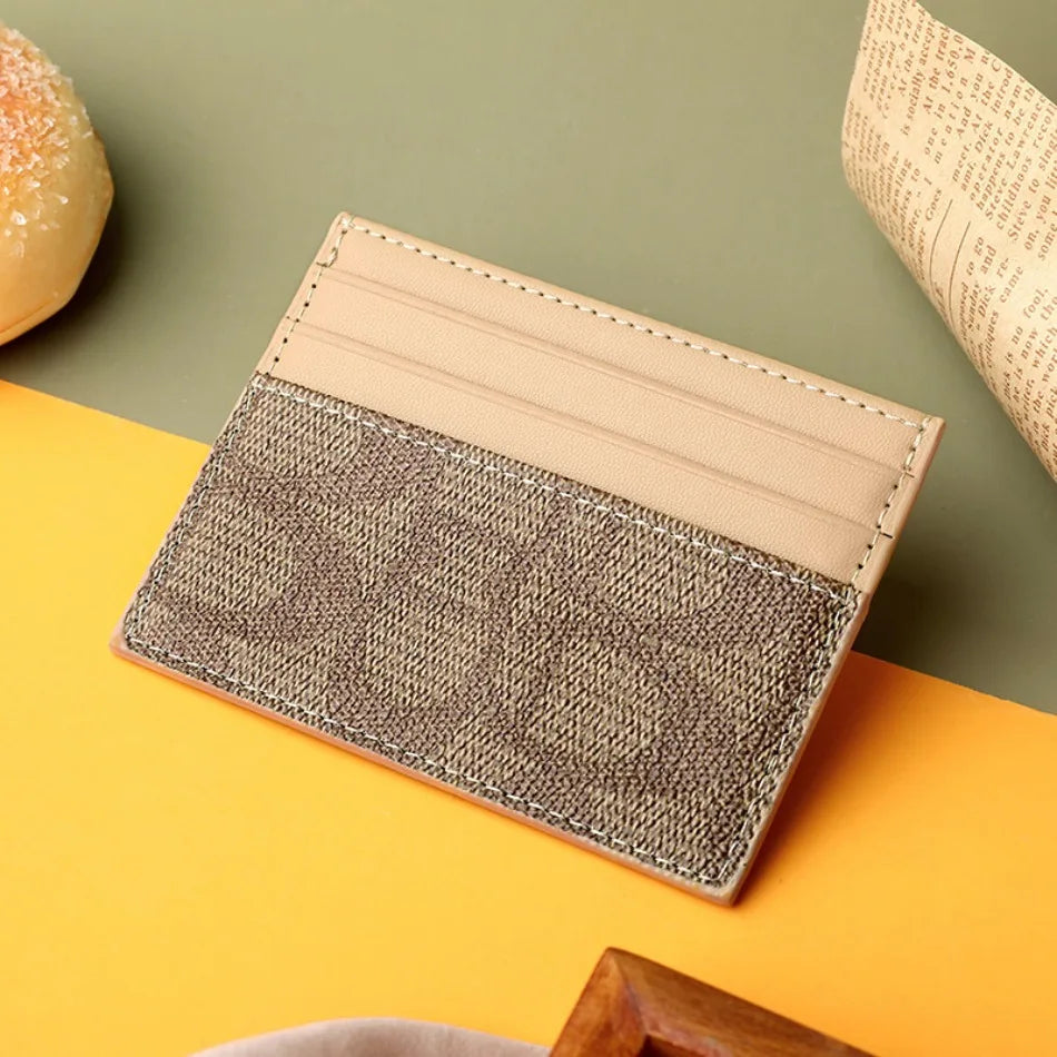 A beige and brown textured card holder purse is shown resting on an orange surface.