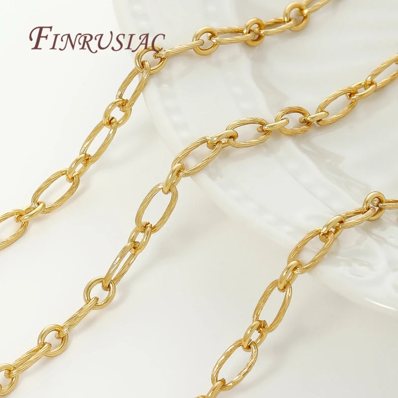 Several strands of gold-colored jewelry chains are displayed on a white surface.