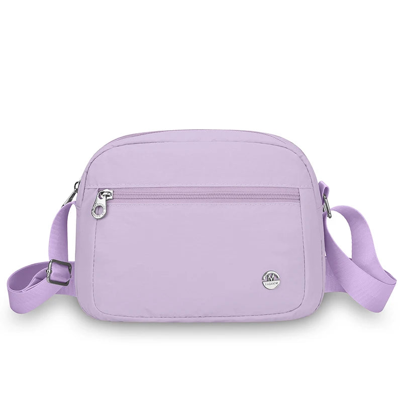 Hellviolette Nylon-Crossbodytasche mit Reißverschluss und verstellbarem Riemchen vor weißem Hintergrund
