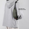 A person is wearing a gray water-resistant jacket with a black nylon waist bag attached to the shoulder.