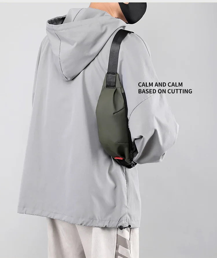 A person is wearing a gray water-resistant jacket with a black nylon waist bag attached to the shoulder.