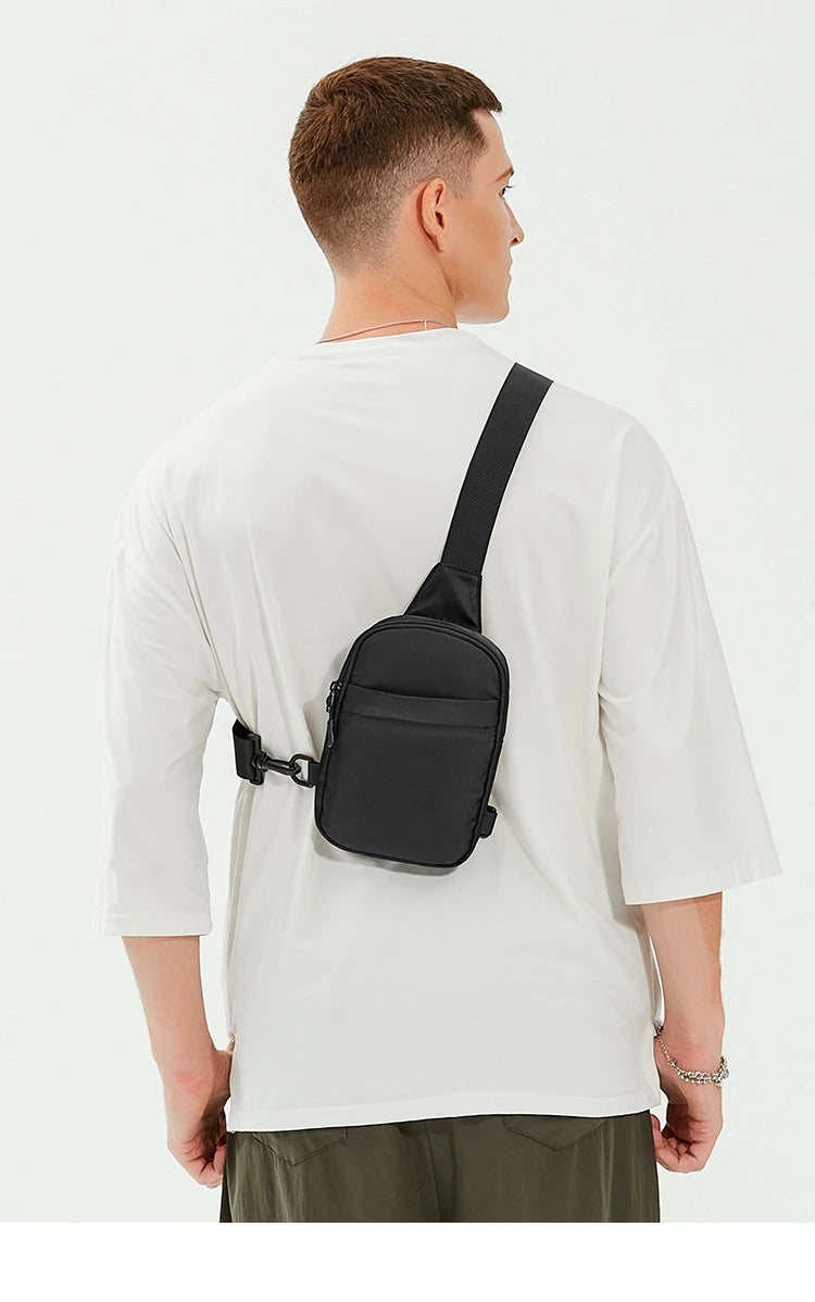 Un hombre con camiseta blanca visto desde atrás, llevando una bolsa cruz multifuncional negra.