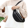 A beige sweater sleeve holds a black nylon crossbody sling bag with a silver zipper detail.