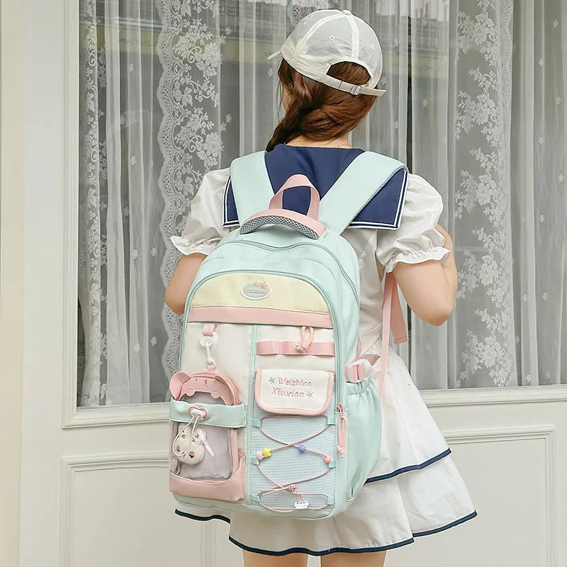 A woman wearing a white dress is shown from the back carrying a light blue and pink Candy Color Campus backpack.