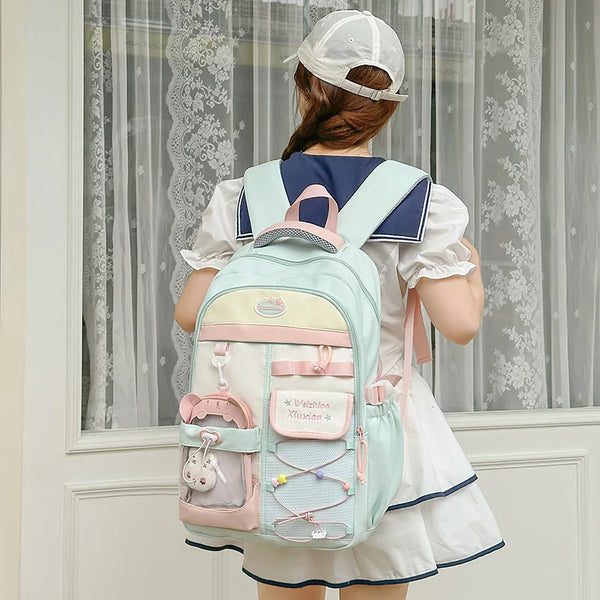A woman wearing a white dress is shown from the back carrying a light blue and pink Candy Color Campus backpack.