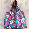 A floral patterned shopping tote bag featuring pink, white, and blue flowers.