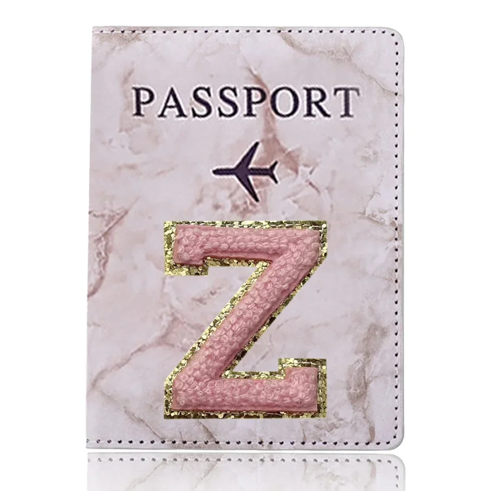 Funda de pasaporte de imitación de cuero rosa con una Z dorada y un ícono de avión.
