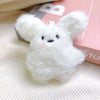 A fluffy white rabbit charm or mascot on a pink background.