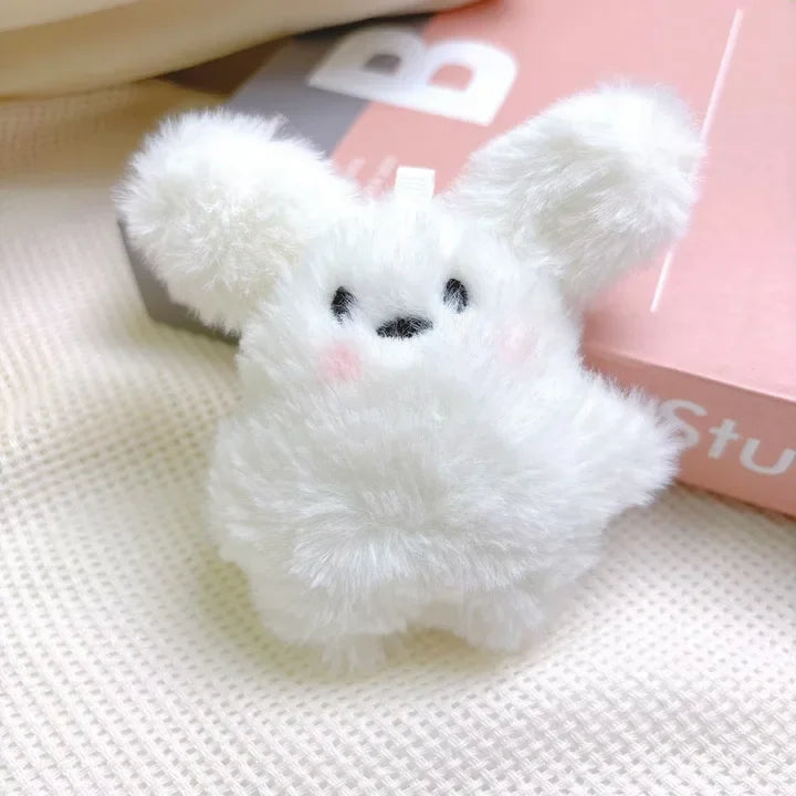 A fluffy white rabbit charm or mascot on a pink background.
