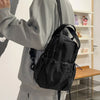 A woman is holding a black casual backpack with a laptop compartment against a white background.