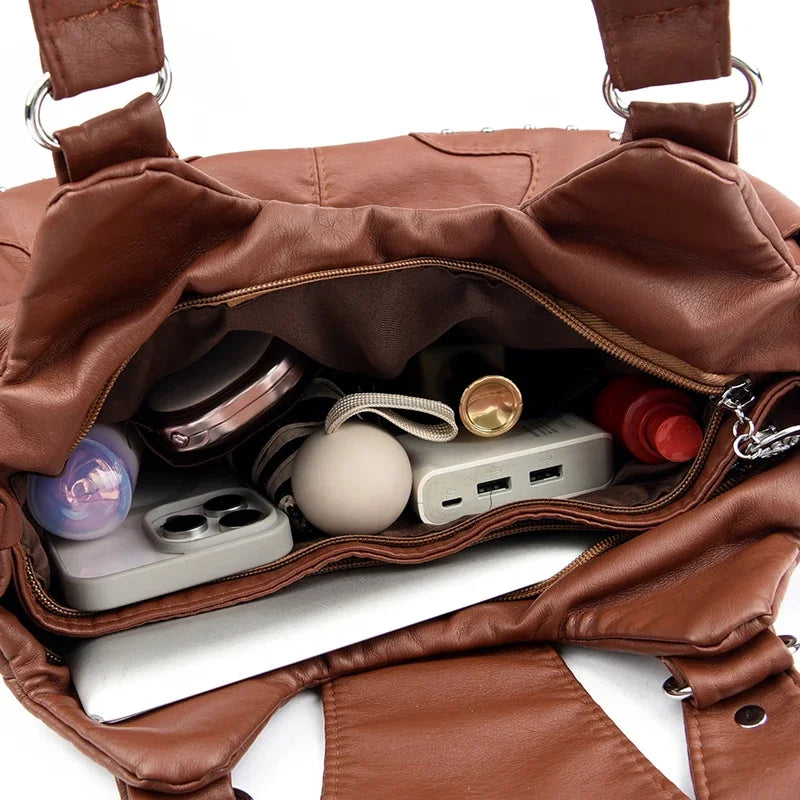 Braune Vintage Soft PU Lederhandtasche, geöffnet und mit kleinen elektronischen Zubehörteilen gefüllt.
