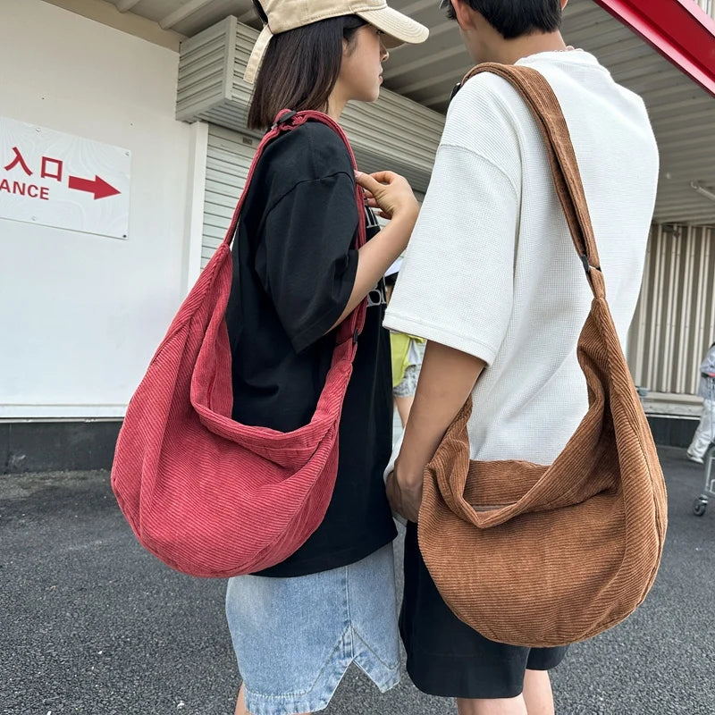 A woman wearing a black shirt and jeans carries a reddish-pink corduroy casual crossbody bag.