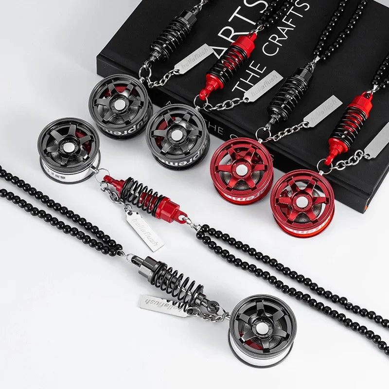A collection of black and red alloy wheel hub brake disc rearview mirror pendants displayed on a dark box.