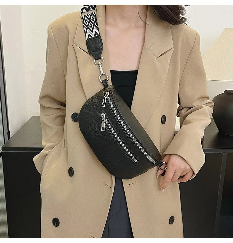 A woman wearing a beige blazer holds a black PU leather multi-pocket crossbody bag with a patterned strap.