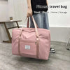 A pink canvas travel bag with multiple compartments is being held by a person in a modern indoor setting.