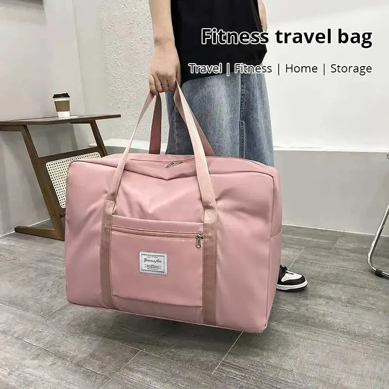 A pink canvas travel bag with multiple compartments is being held by a person in a modern indoor setting.