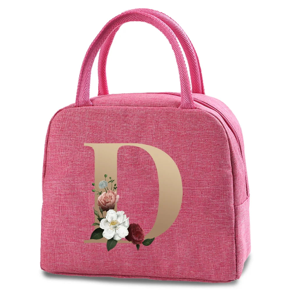 A pink insulated canvas lunch bag featuring a gold letter D design with floral accents.