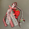 A red strawberry bag charm keychain featuring a fabric bow and white lace details.