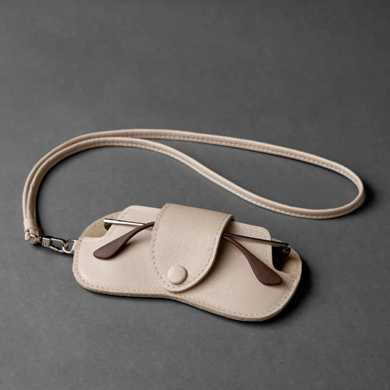 A light beige PU leather storage case for eyeglasses with a leather strap and chain.