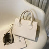 Sac à main en cuir PU blanc minimaliste avec poignée supérieure, posé sur une surface claire.
